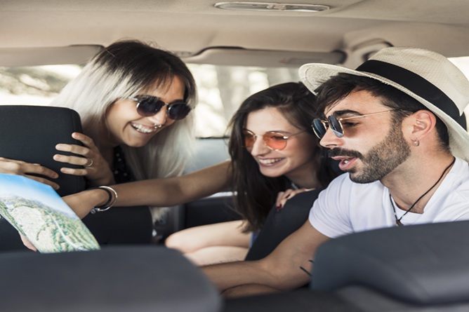 young friends sitting inside modern car looking map